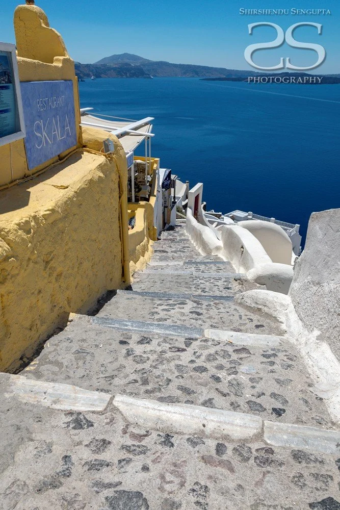 stairs going down to the sea near white houses church bell towers blue domes oia imerovigli firostefani fira village santorini greece caldera volcanic island
